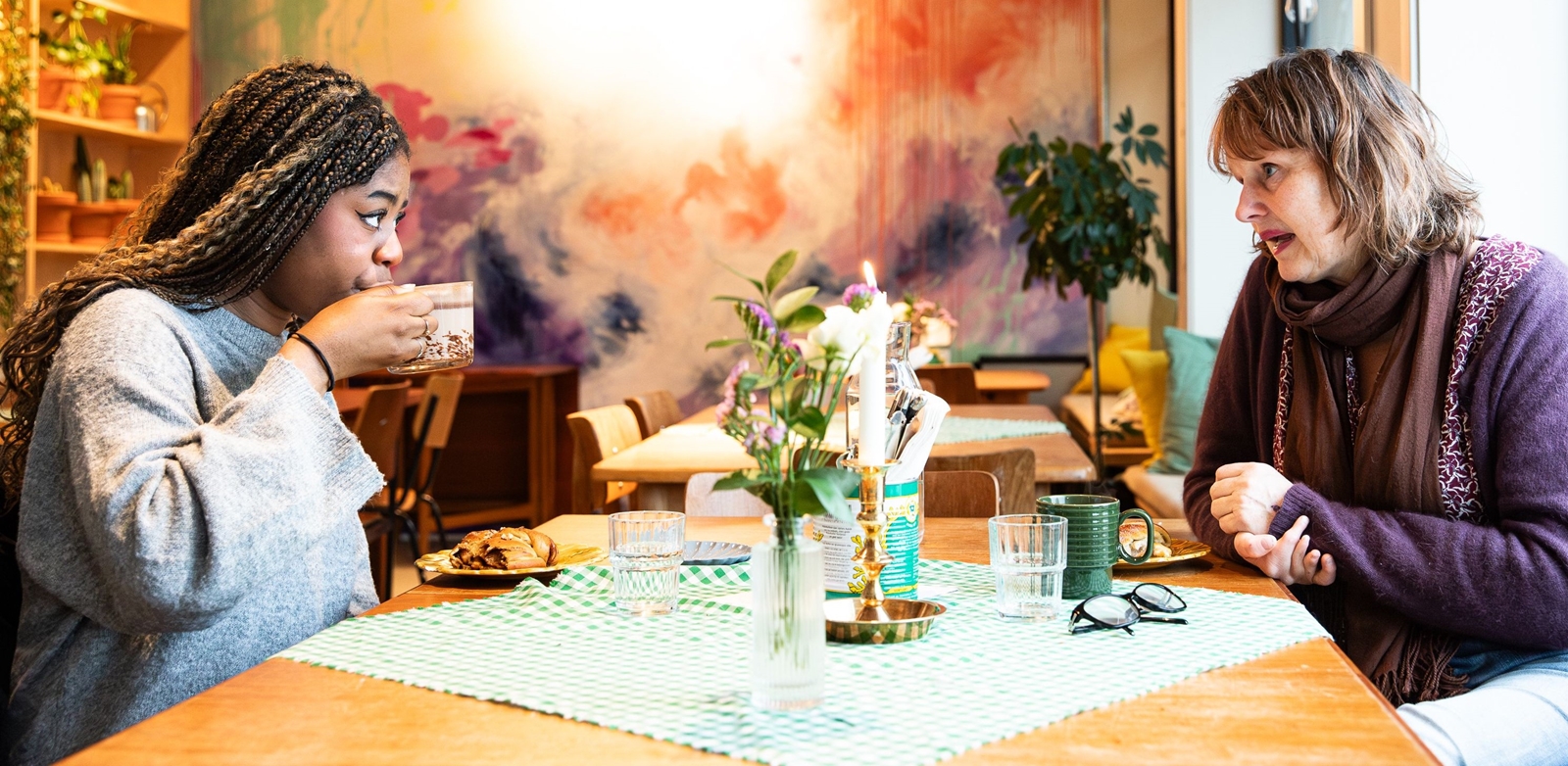 Mentor og deltaker i samtale over kaffe, illustrerer støtten og veiledningen som tilbys gjennom Røde Kors' mentorordning for familier.