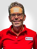 Portrettbilde av en voksen mann med kort hår, briller og mørke grå hår, med røde kors uniformen på.