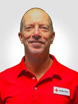 Portrettbilde av en voksen norsk mann uten hår men med grå skjeggstubber, også med røde kors uniformen på.