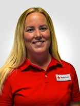 Portrettbilde av ei ung kvinner med langt blondt hår og stort smil, med røde kors uniformen på.