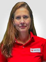 Portrettbilde av ei kvinne med langt brunt hår, to røde øredobber, et smått smil, med røde kors uniform på.