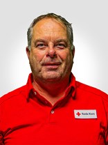 Portrettbilde av en voksen mann med kort brunt hår, hvor delevis av det har blitt grått og er glattbarbert, han har også på seg røde kors uniform.