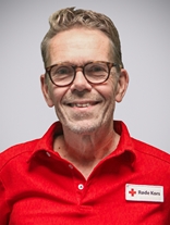 Portrettbilde av en voksen mann med kort hår, briller og mørke grå hår, med røde kors uniformen på.