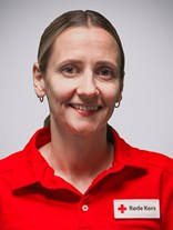 Portrett bilde av ei kvinne med langt brunt med lengde ned til nakken, bundet i en hestehale med strikk, to øredobber, et smått smil, med røde kors uniform på.