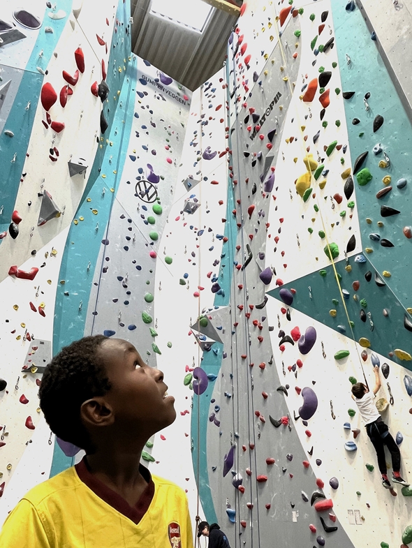 Deltaker fra Røde Kors Familiesenter ser opp på klatreveggen i Klatreverket i Kristiansand, klar for å prøve seg på høyden.