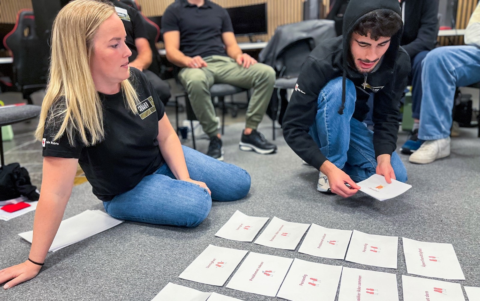 To unge voksene som sitter og sorterer rundt lapper de har fått fra kurset.