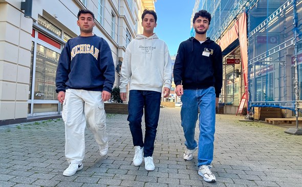 Tre voksene ungdommer som går ned en gate.