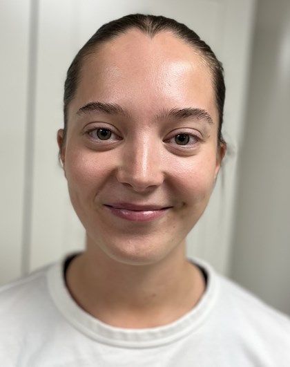 Portrettbilde av en ung kvinne med et fint smil som ser rett på kamera og har på seg en skjorte.