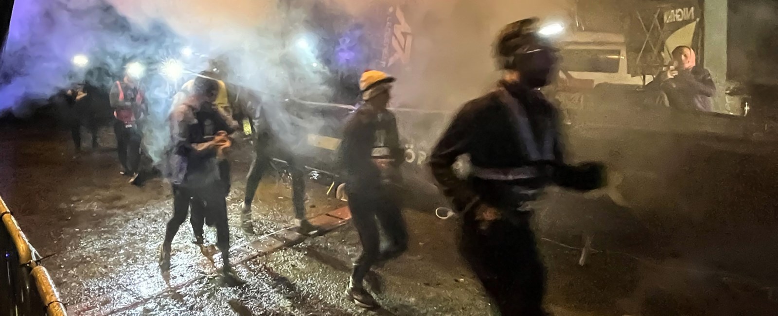 Fem frivillige fra Kristiansand Røde Kors Hjelpekorps poserer foran en Røde Kors-ambulanse etter en kveldsvakt under nightrun.