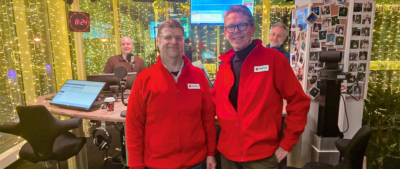 Fire personer står i et radiostudio pyntet med lyslenker. Foran står Yngve Stiansen og Håvard Raustøl, begge i røde Røde Kors-jakker. Bak dem står Alfred Solgaard og Rabih Costantine ved studiopulten med mikrofoner og skjermer. Stemningen er uformell og vennlig.