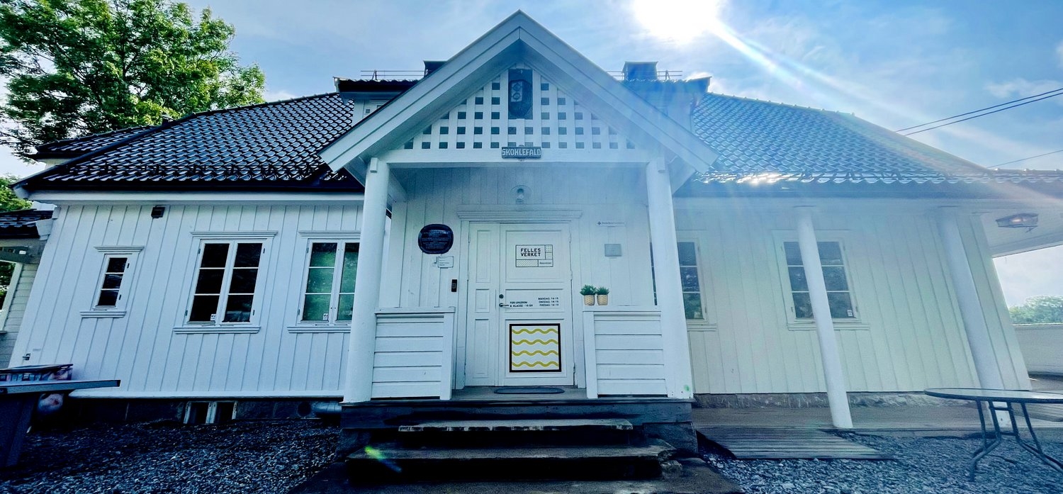 Hvitt hus med trær og sol. 