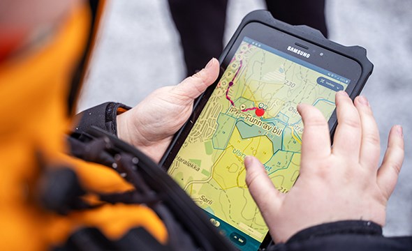 hender som holder en iPad som viser et kart