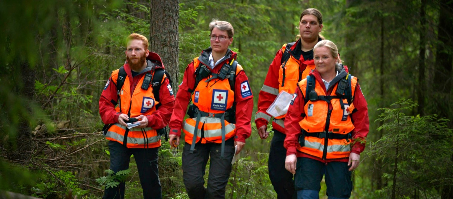 Fire personer ikledd Røde Kors-uniform som patruljerer i skogen