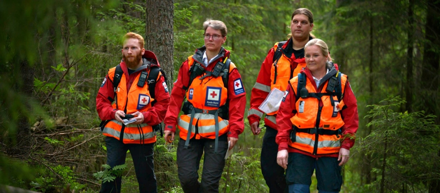 Fire personer ikledd Røde Kors-uniform som patruljerer i skogen