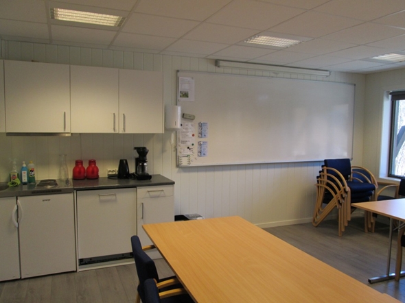 Et rom med whiteboard og en liten kjøkkenkrok