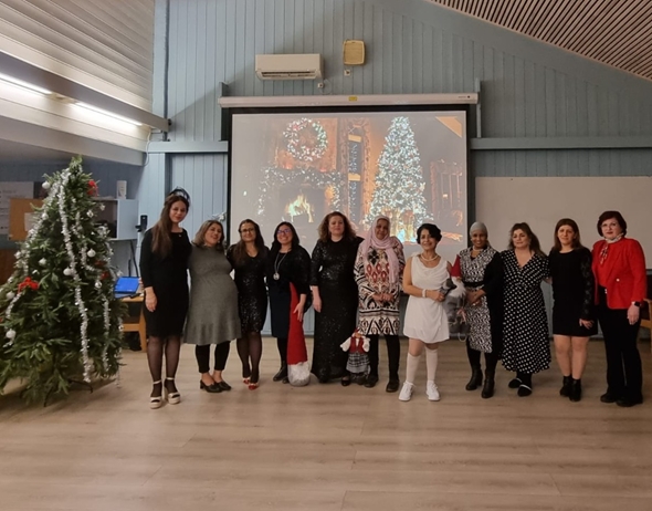 11 kvinner står på rekke foran julepynt i et stort rom