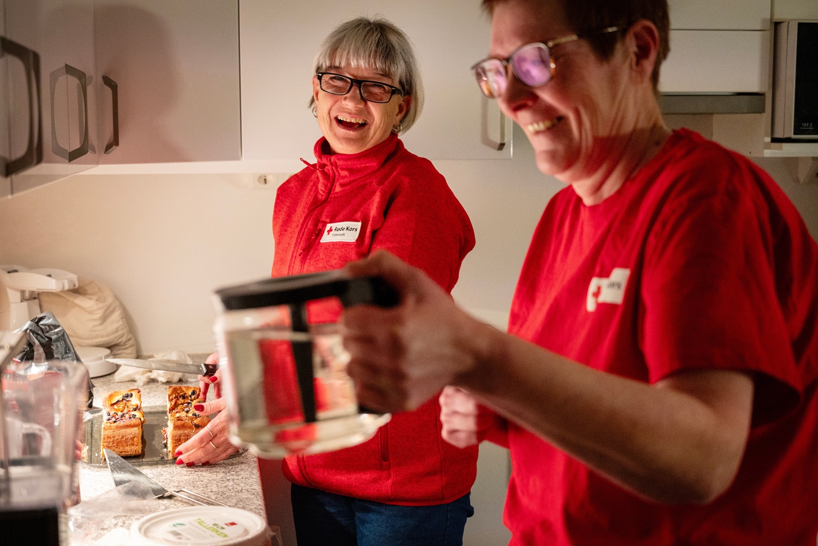 To kvinner som koker kaffe og tilbereder kake.