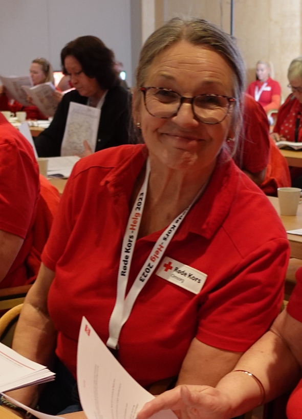 Kvinne  som smiler mot kamera fra årsmøtesal