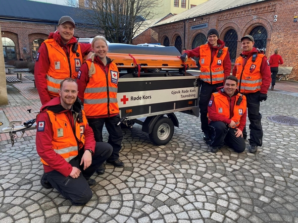 Hjelpekorpsere som står i en gruppe foran en Røde Kors-bil