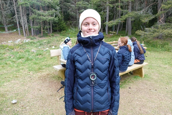 Jente som ser i kamera med mange ungdommer på en benk bak