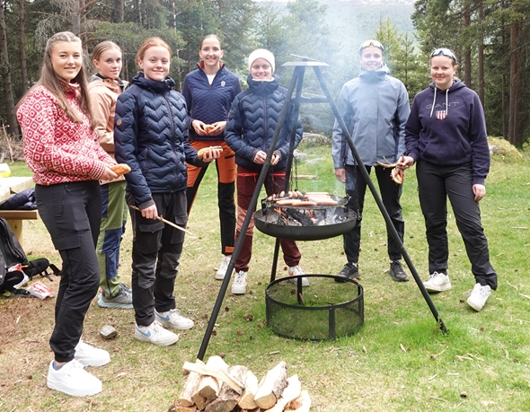 Mange jenter i skogen foran en bålpanne