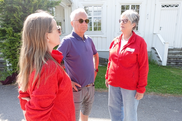 Tre mennesker som står sammen ute på asfalten og snakker sammen