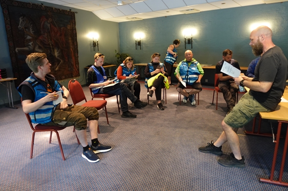 Foto av mennesker i ring på stoler.