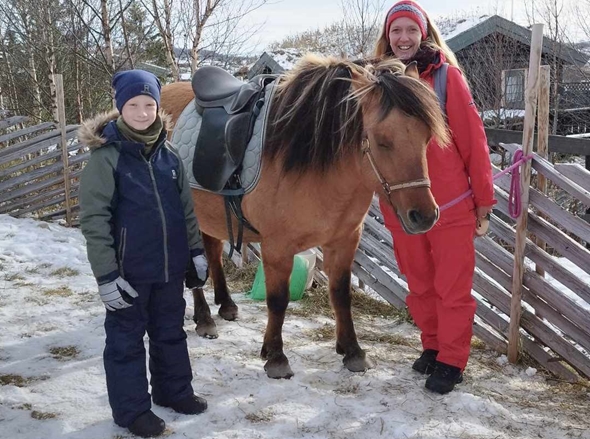 Et barn og en voksen kvinne står sammen med en hest.
