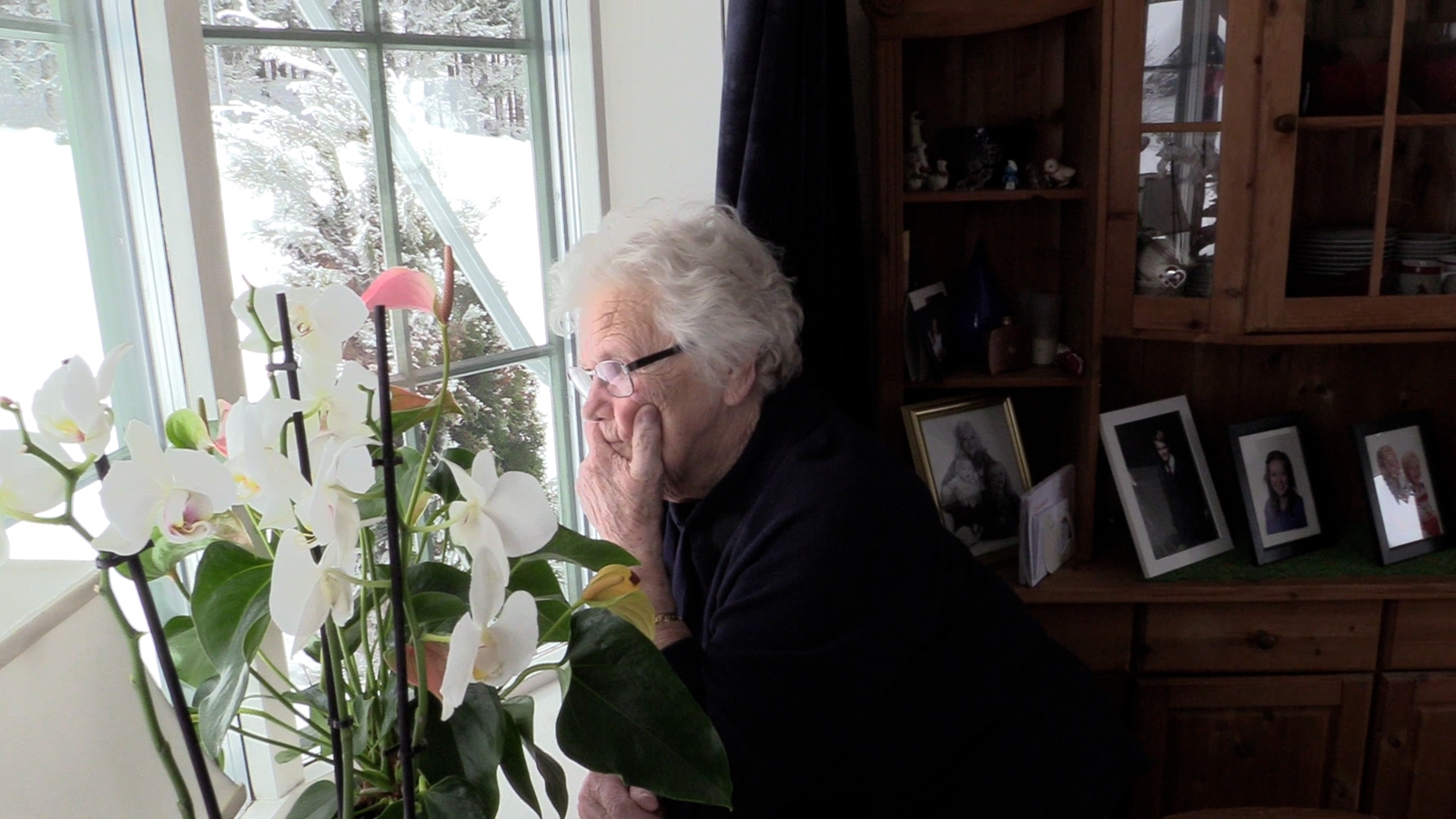 eldre kvinne ser ut av vinduet i stua