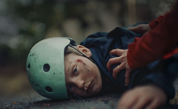 Gutt med hodet på asfalt, skadet