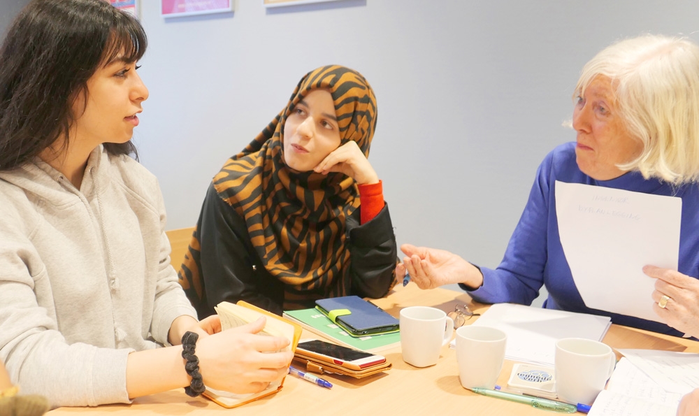 Bildet viser en norsklærer som lærer norsk til to elever.