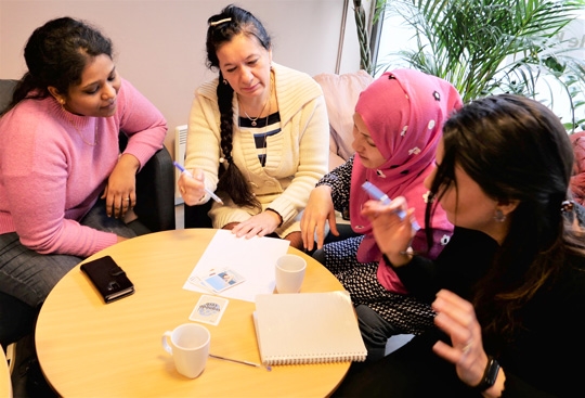 Tre kvinner følger med når en norsklærer forsøker å lære dem norsk. 