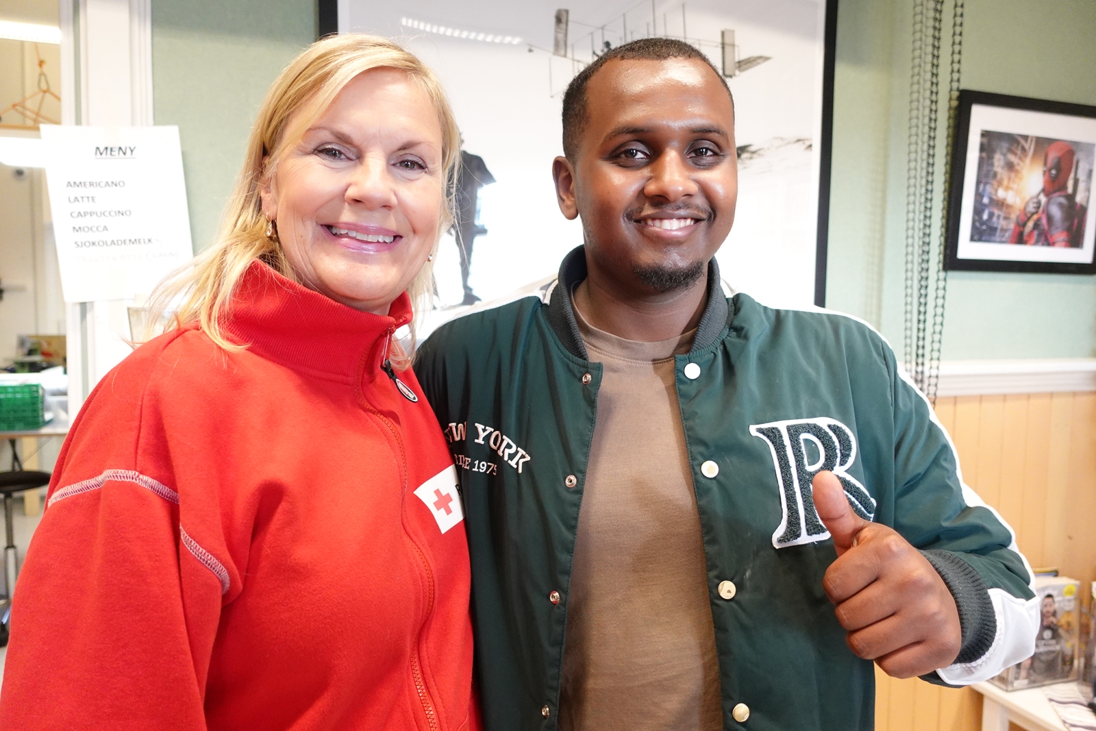 En kvinne i Røde Kors-klær og en mann som holder tommelen opp.