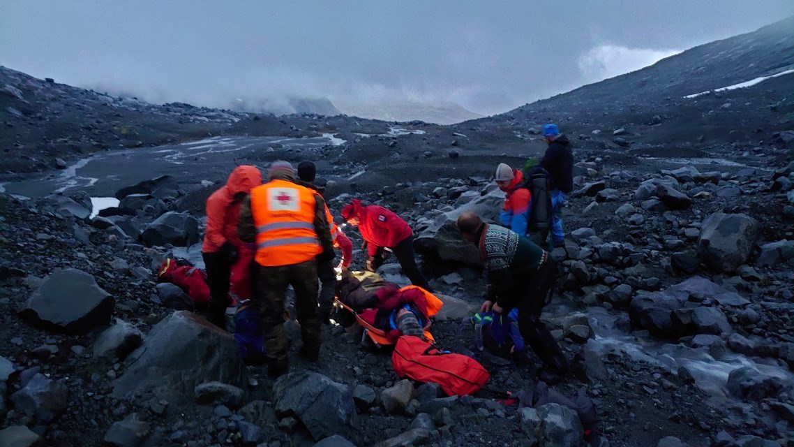 Frivillige mannskaper fra Røde Kors hjelper skadd mann på fjellet