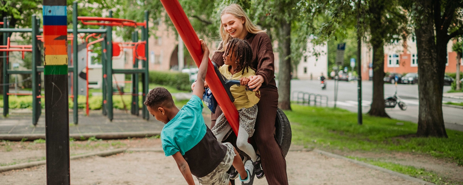 To barn som leker med en frivillig på huskestativ
