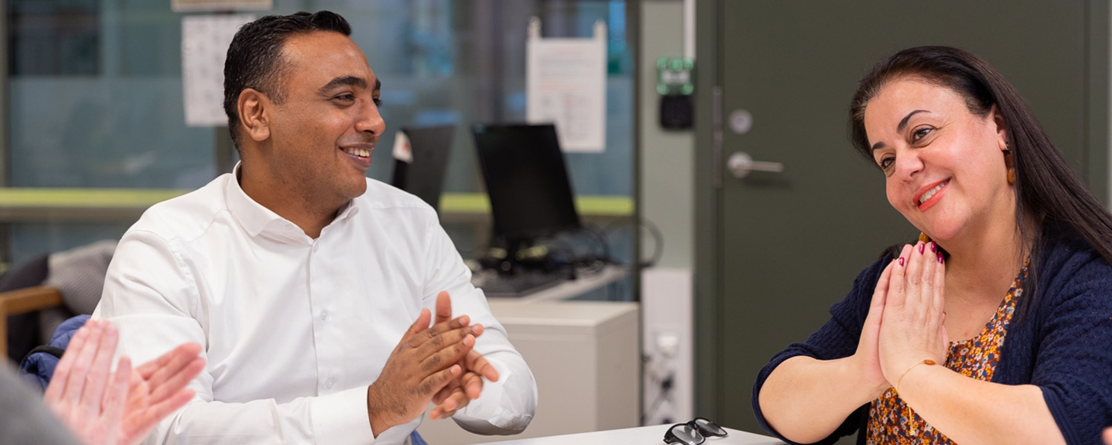 A group of people are sitting around a table studying norwegian words