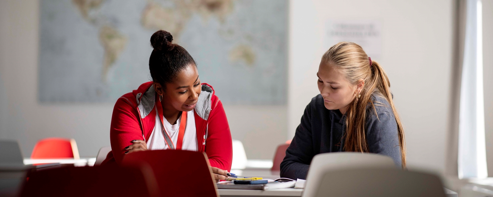 Frivillig kvinne som hjelper annen kvinne med lekser