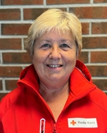 Kvine med kort blondt hår ser mot kamera