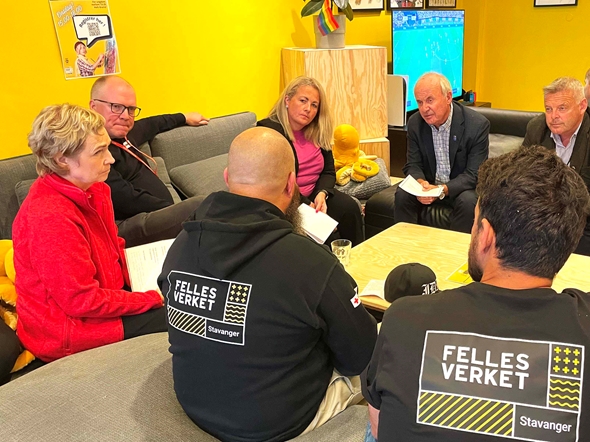 Syv personer sitter i sofa, og snakker sammen.