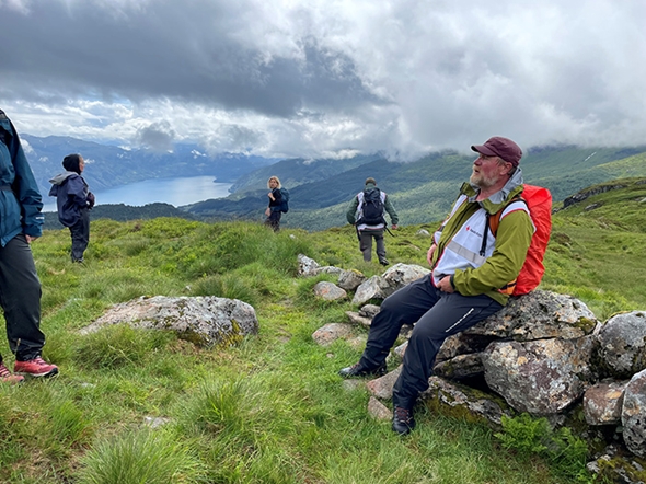Mann sitter på steingjerde.