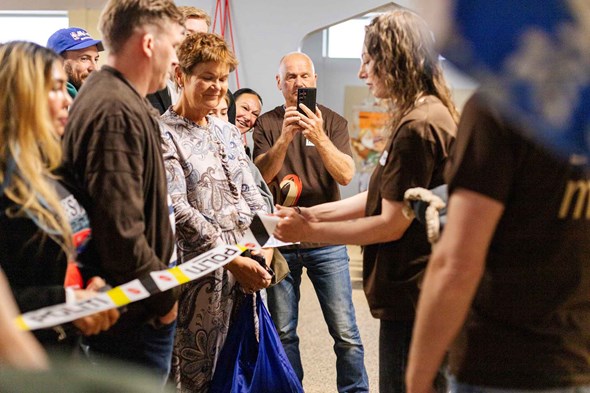 Kvinne klipper snor mens flere mennesker ser på.