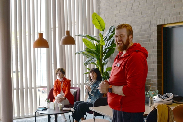 Smilende person i forgrunnet, flere personer i bakgrunnen.