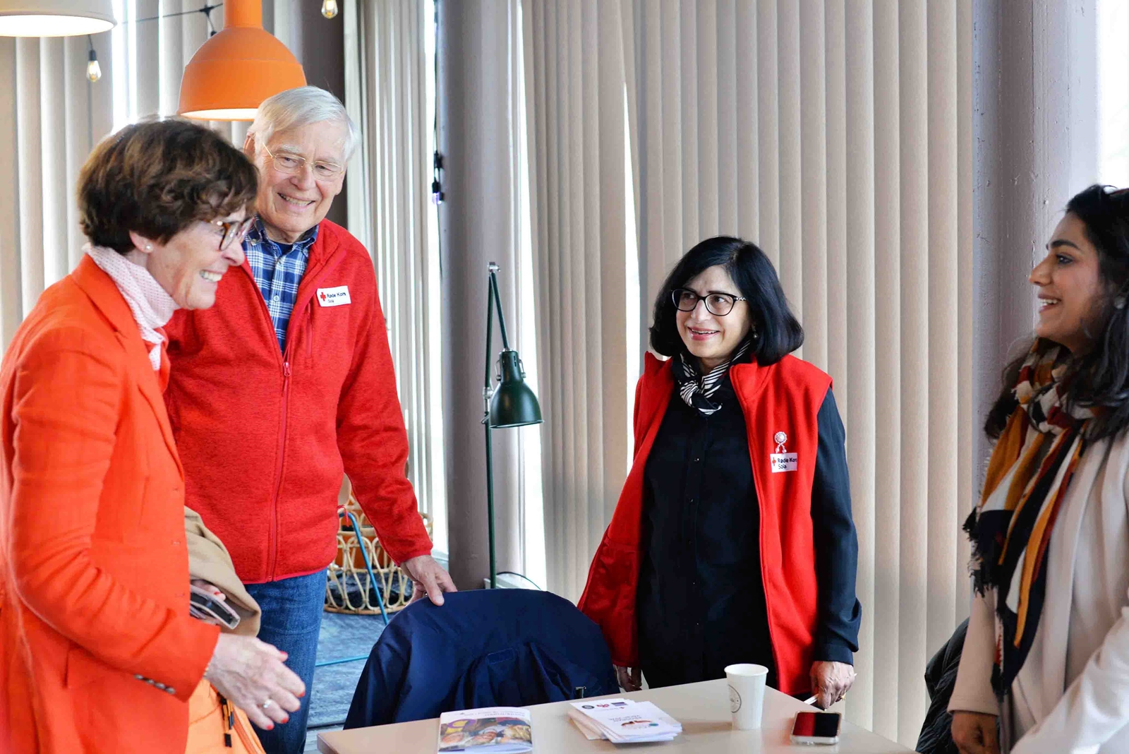 Foto av fire personer som står rundt et bord i et lyst møterom. 