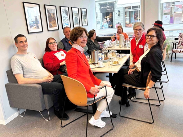 Smilende personer rundt et bord dekket til lunsj.