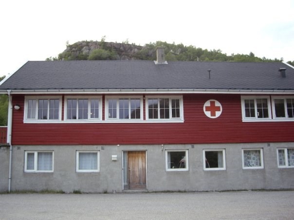 Rødmalt hus med Røde Kors-logo.