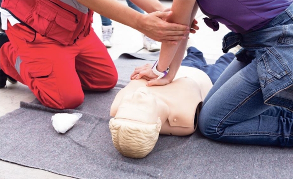 Mennesker som sitter på bakken og øver på førstehjelp