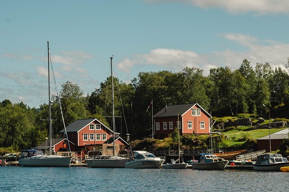 Raude hus langs brygge med fleire båtar