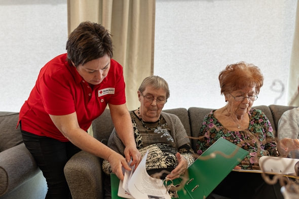 Røde Kors frivillig hjelper med å bla i songperm