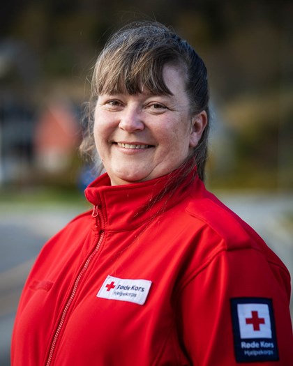 Kvinne i Røde Kors jakke smiler