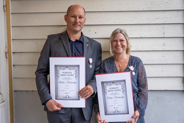 Mann og kvinne med medalje stilt opp mot veggen.